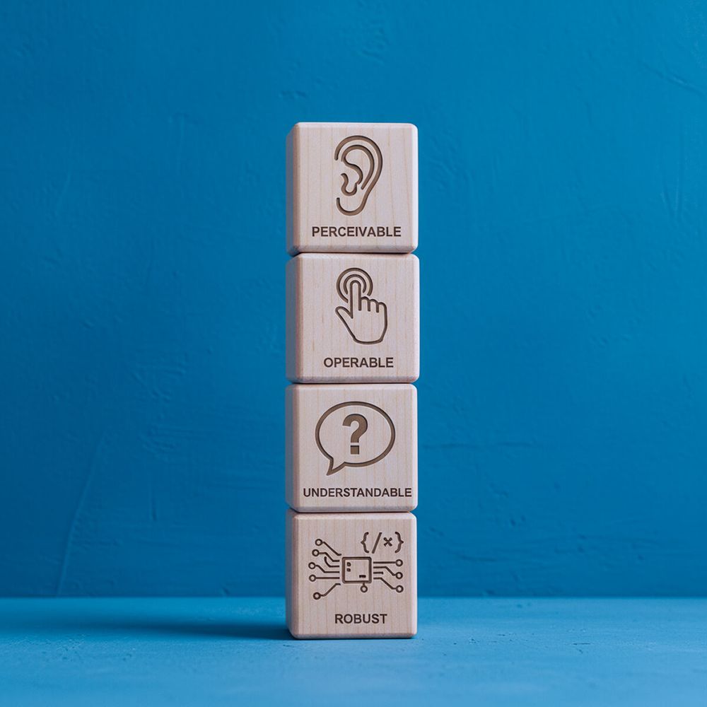 Quattro cubi di legno impilati, ciascuno con un’icona per i principi POUR dell’accessibilità: Percepibile, Operabile, Comprensibile, Robusto