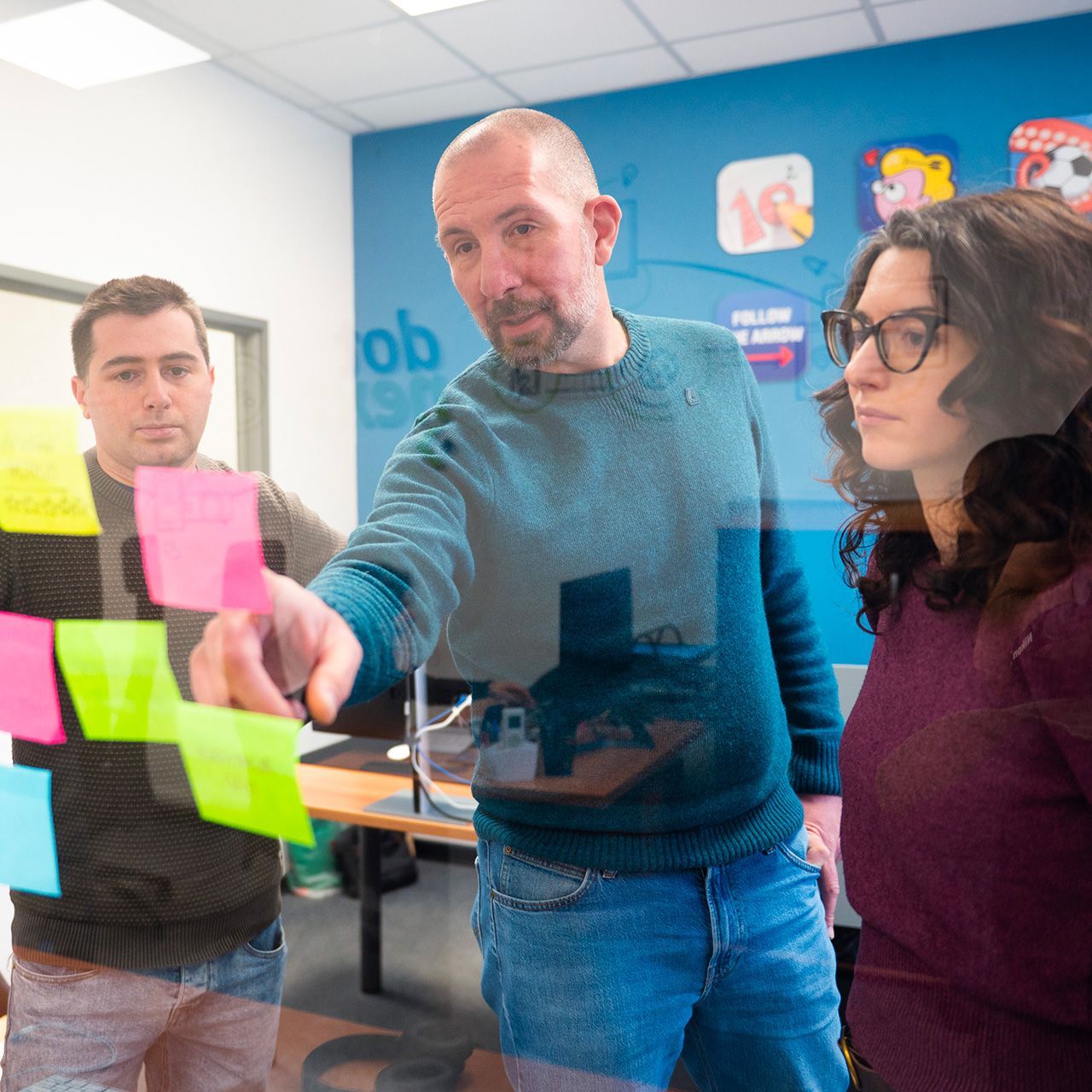 Il team di Dot Next che attacca post-it al vetro durante un workshop di design thinking